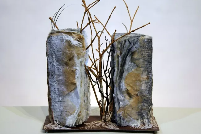 Sculpture en papier de Viviane Fontaine, intitulée ”Entre deux”, représentant un arbre qui pousse entre deux piliers